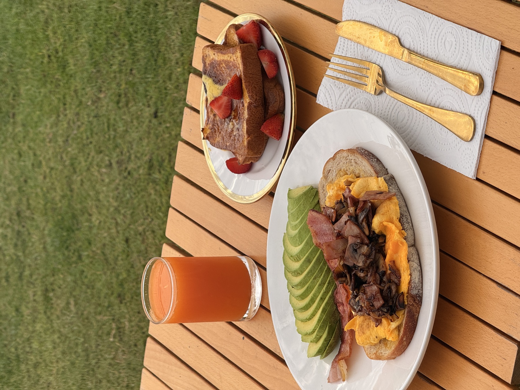 Breakfast on the lawn — eggs, avocado, toast, French toast, fresh juice