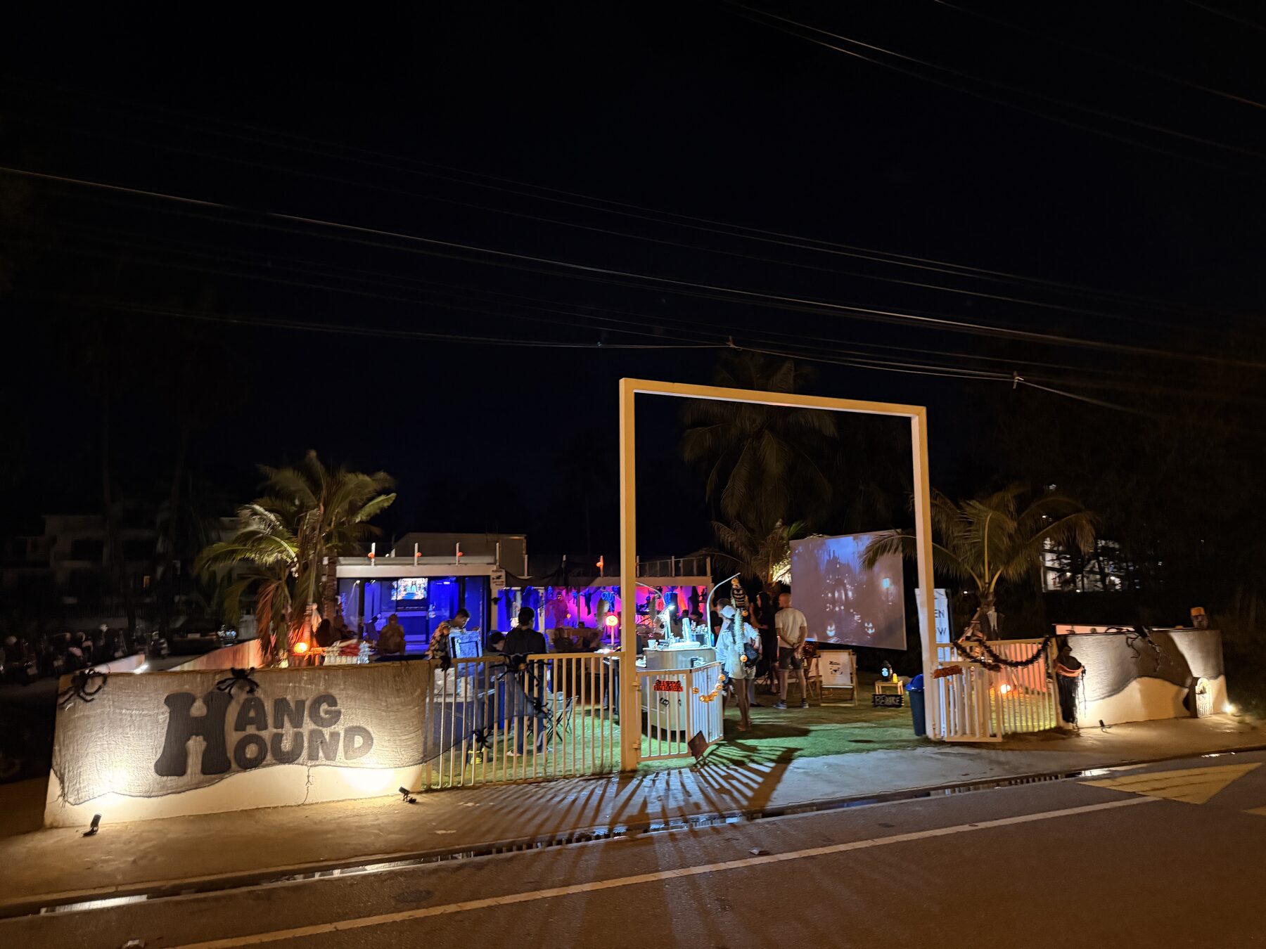 The compound at night — gate with cinema glowing through